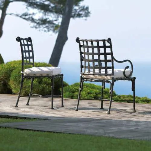 Tuscan style black cast aluminum outdoor dining chairs on a wooden deck overlooking water