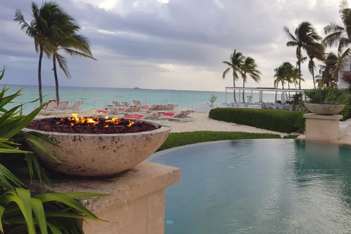 Concrete firebowls sitting on pedestals at the edge of a beachside infinity pool