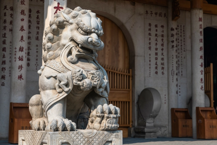 Female Chinese guardian lion with whirled mane in front of large doorway