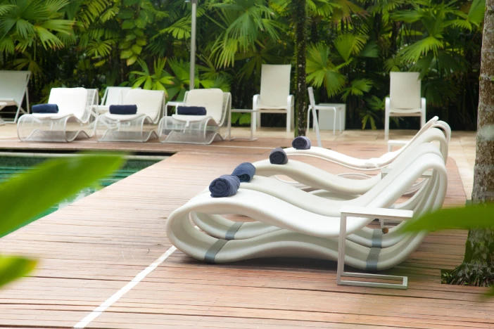 Modern abstract styled white sun loungers arranged around a swimming pool