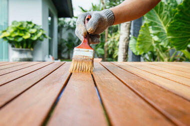 Person applying stain to a wood patio table