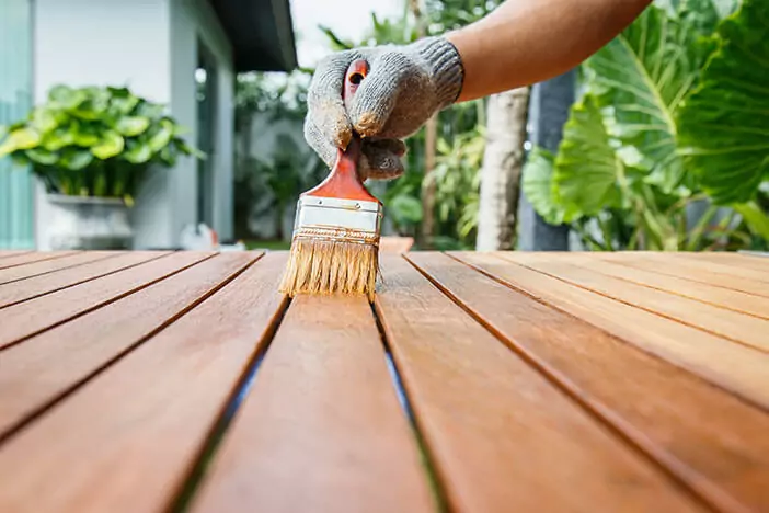 Person applying stain to a wood patio table