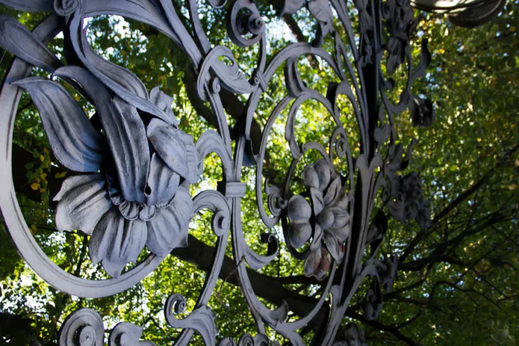 Black iron garden fence with large floral blooms, wavy leaves and curling stems