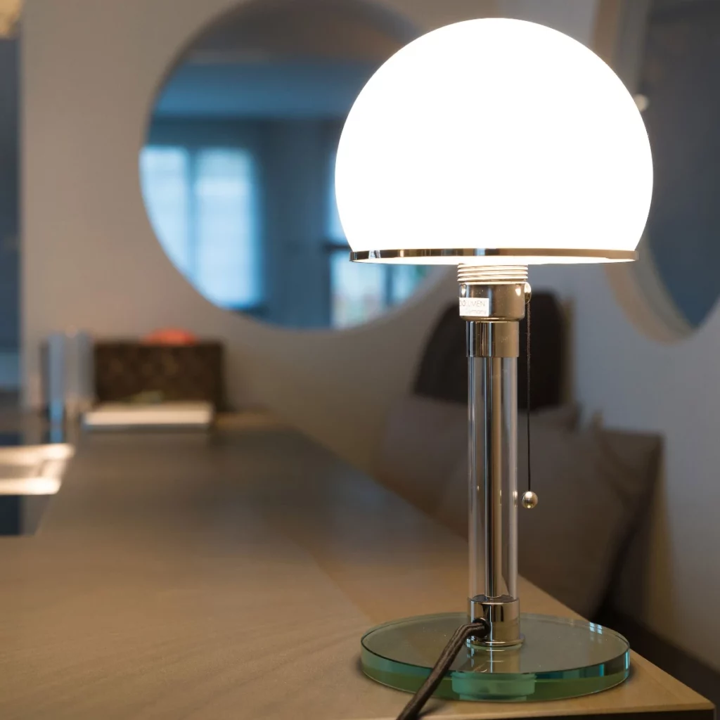 Minimalist table lamp with round green glass base, clear stem and white semi-globe diffuser