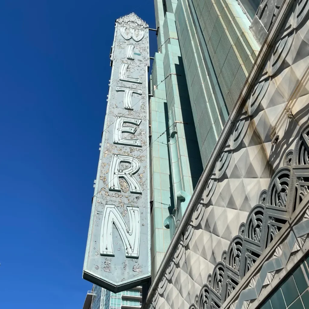 Vertical theater sign with zig zag Art Deco detailing on greenish building