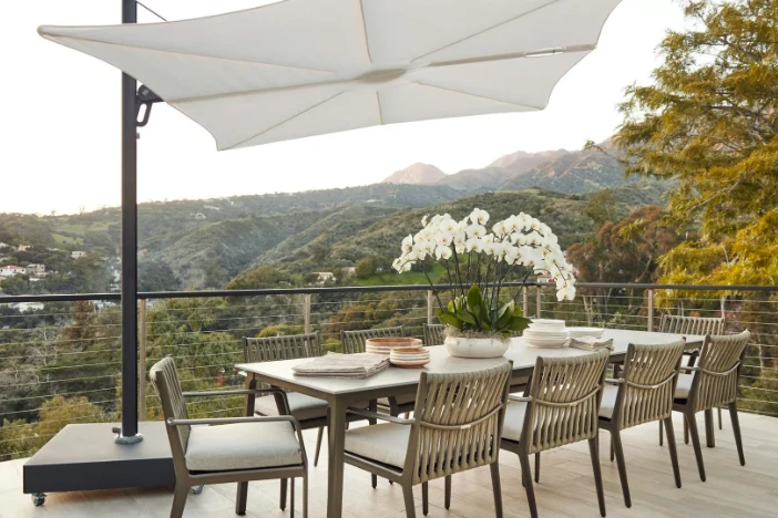 Modern grey patio dining armchairs with woven rope backrests around a rectangular table and shaded by a cantilever umbrella with a square white canopy