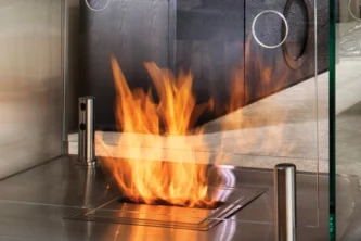 Close-up of bio-ethanol burning fireplace insert with tempered glass wind guard and stainless steel firebox