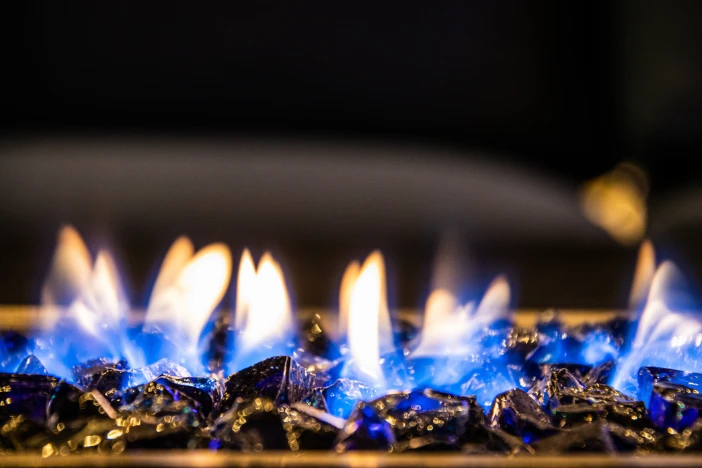 Close-up of blue gas flame and decorative black glass charcoal