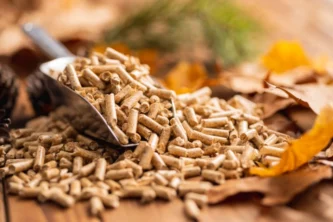 Close-up of compressed wood pellets with a metal scoop on a wooden table