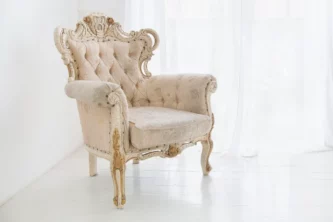 Ornate shabby chic crested armchair in washed white with gold accents and tufted cream upholstery