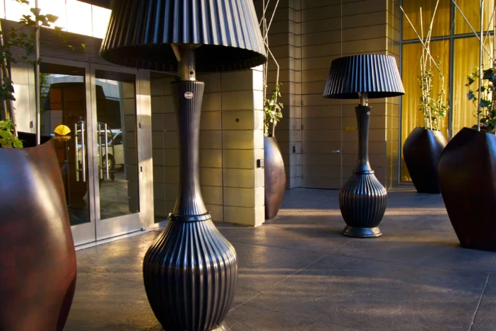 Two oversized black lamp-style patio heaters with ridged surface outside of a hotel doorway