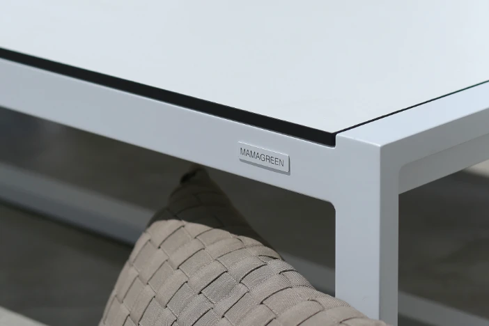 Close-up of white aluminum patio coffee table and taupe throw pillow