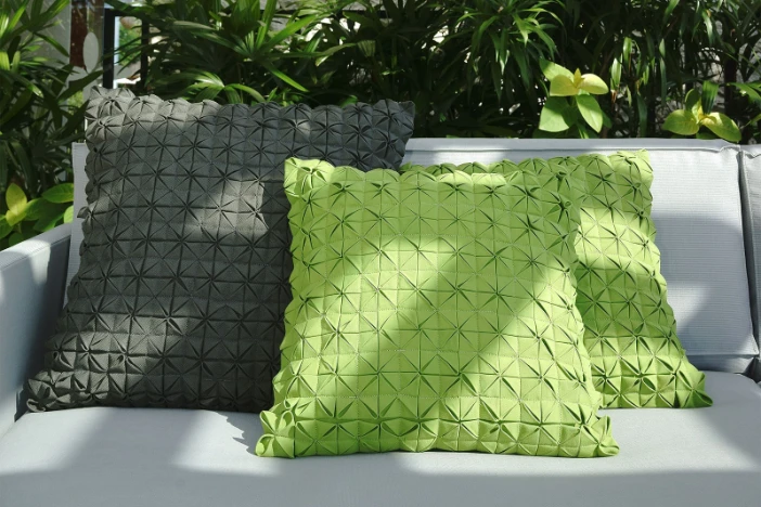 Textured light green and khaki outdoor throw pillows on a white upholstered sofa