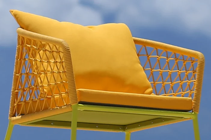 Yellow metal tube patio chair with open-weave body, thin seat cushion and large back pillow