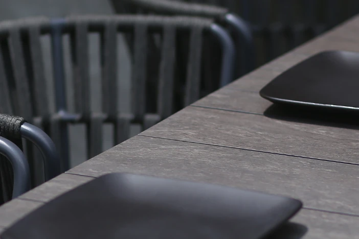 Close-up of dark high-pressure laminate tabletop with black plates and patio dining chairs