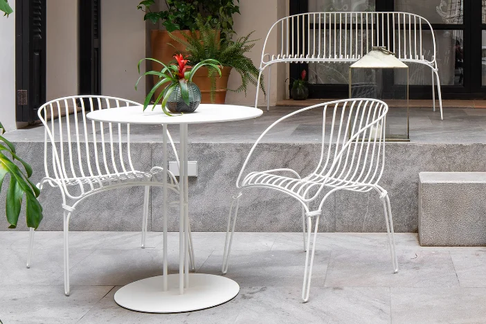 Two metal wireframe patio chairs, loveseat and small tables with white powder-coated finish