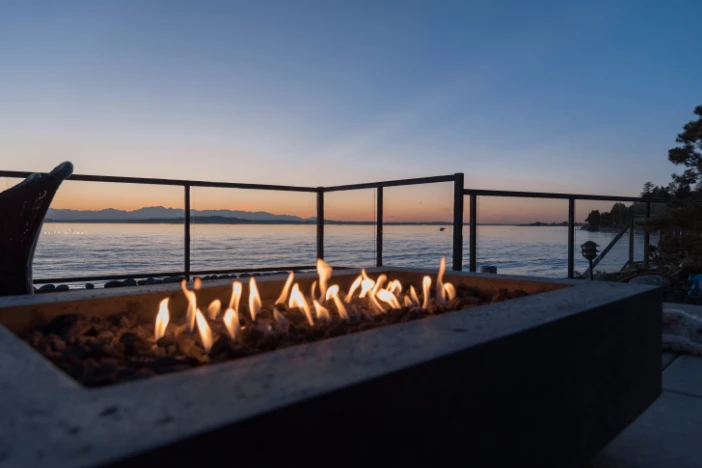 Gas lit rectangular outdoor fire pit on a beach house patio at sunset