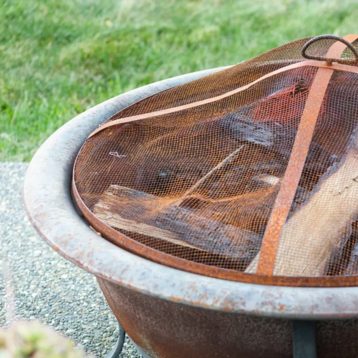 Terracotta fire bowl with spark guard covering unlit firewood