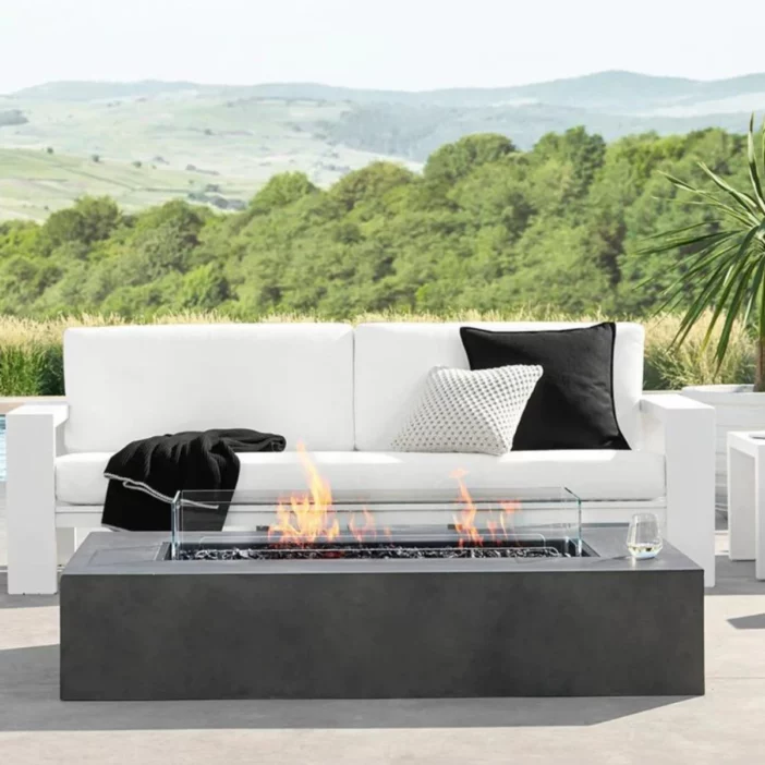 Rectangular fire pit table with dark grey finish in front of a white outdoor sofa