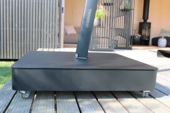 Close-up of charcoal grey cantilever umbrella base with wheels on a hardwood deck