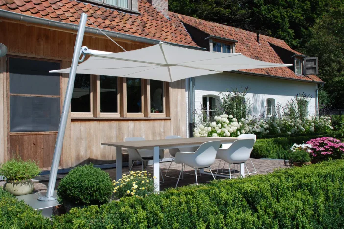 Cantilever patio umbrella with aluminum forward leaning pole and square white canopy over a dining set