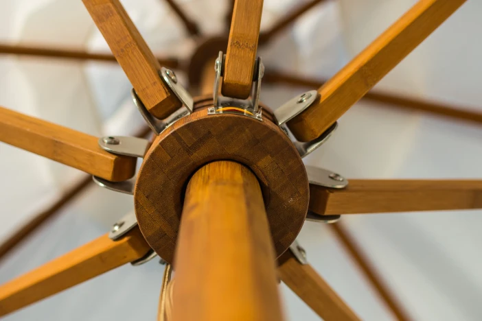 Detailed view of a bamboo umbrella pole running through the hub and rib assembly below a white canopy