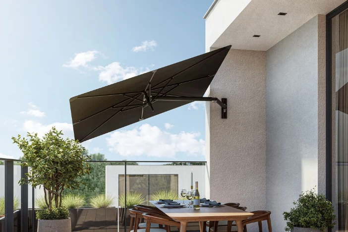 Wall-mounted offset umbrella with square black canopy on off-white patio wall on a sunny day