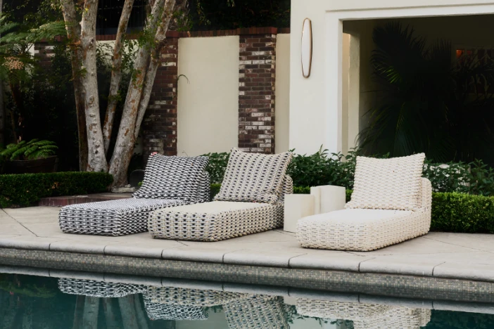 Three neutral-colored silicone weave outdoor chaise lounges with headrest pillows next to a pool