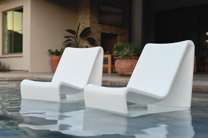 Two abstract white polyethylene chairs sitting in the shallow end of a pool