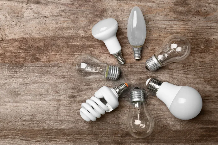 LED, incandescent and fluorescent lightbulbs arranged in a circle on wooden background