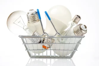 Metal shopping basket with bright blue handles full of a variety of light bulbs