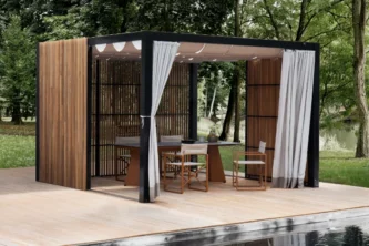 Modern rectangular canopy with wood slat sides, fabric roof and white curtains shading a dining set on a light deck next to a pool