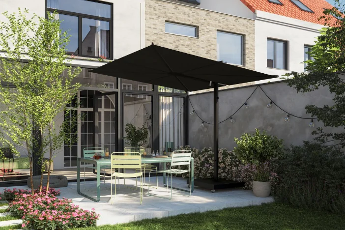 Small row house backyard patio with a black cantilever umbrella with a square canopy shading a green metal dining set