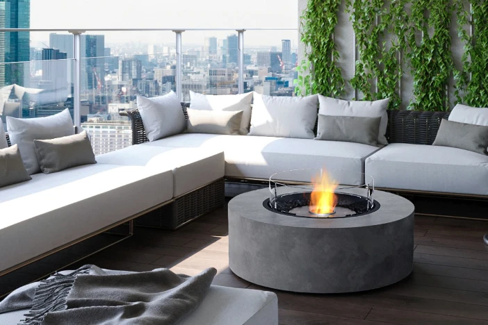 Modern outdoor sectional with thick white seat cushions around a round grey concrete fire table on large urban terrace