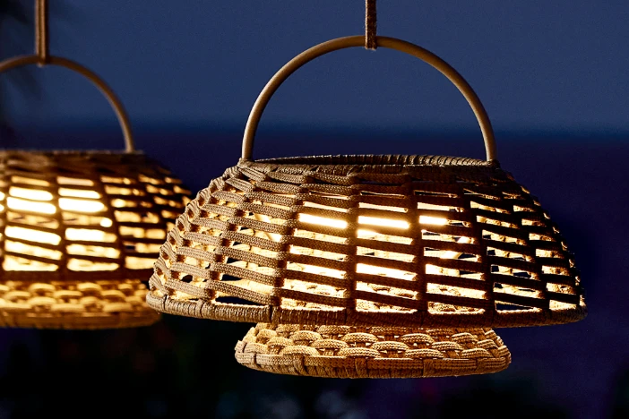 Two woven light brown outdoor pendant lights at night