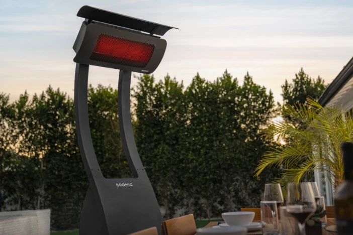 Black modern freestanding patio heater next to a dining table at dusk