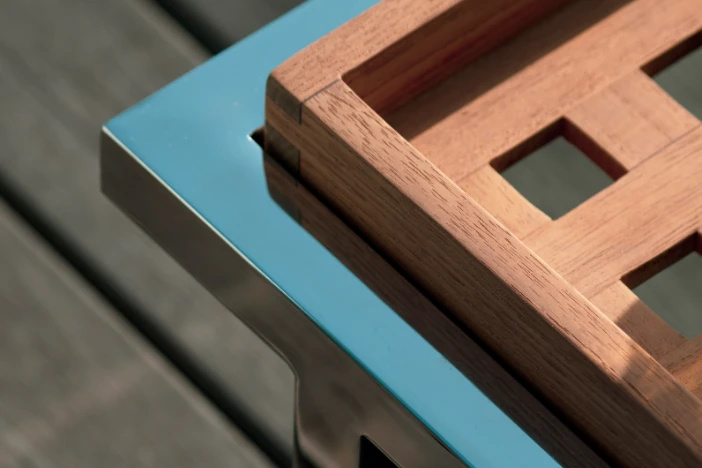 Close-up of stainless steel frame and removable teak tray on a hardwood deck