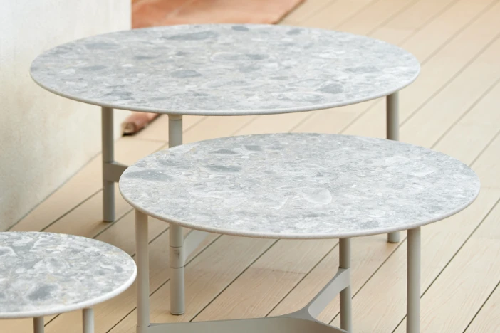 Three round light taupe coffee tables with beige marbled ceramic tabletops on a patio deck