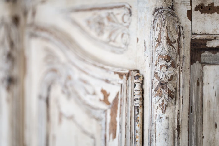 Close-up of the corner of a distressed white cabinet with chipped paint