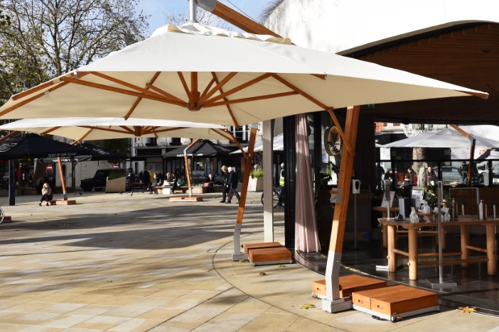 Cantilever patio umbrellas with bamboo frames, bases and natural canopies outside a restaurant