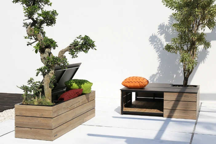 Teak outdoor storage bench and coffee table with integrated planters with small trees on a patio