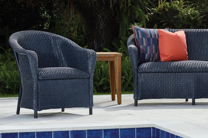 Black all-weather wicker lounge armchair and loveseat next to a swimming pool