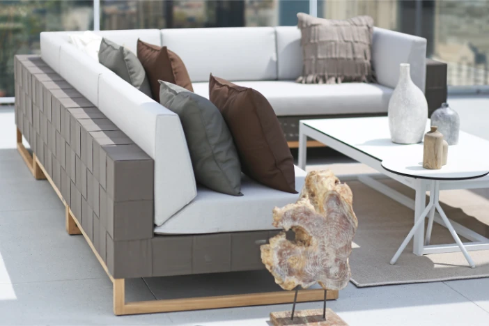 Modern sectional sofa with woven taupe body and white upholstery on a patio