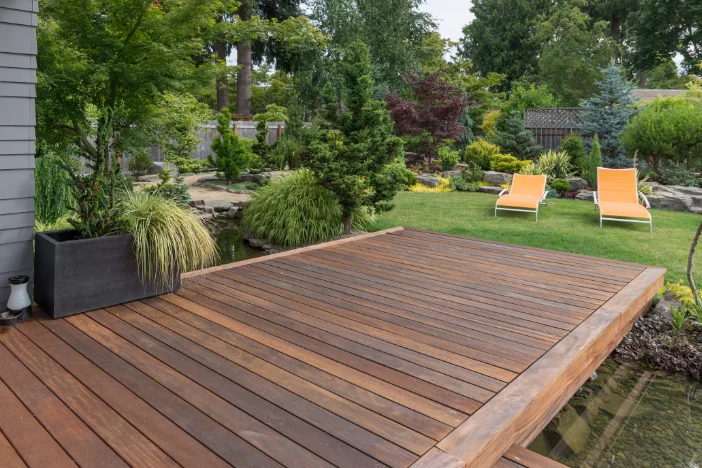 Rich brown hardwood deck in lush backyard with two golden yellow sunloungers