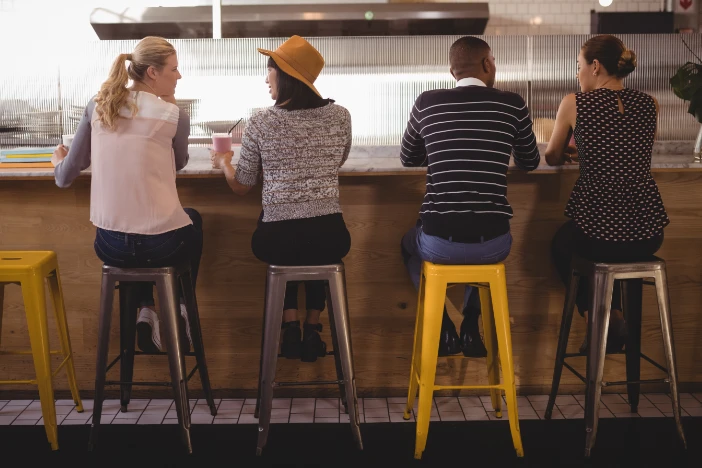 Four people sitting on silver and yellow counter stools at a marble kitchen countertop