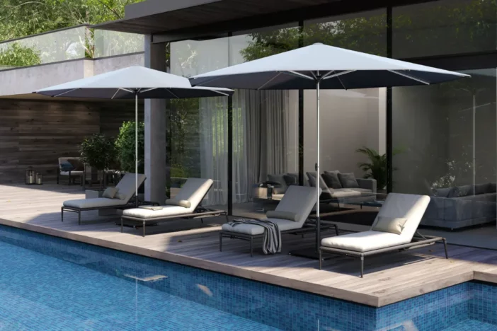 Adjustable chaise sunloungers sitting beneath market umbrellas poolside