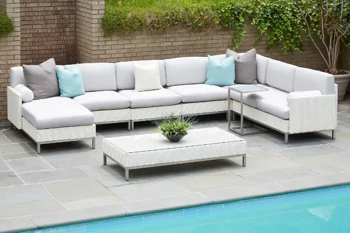 White upholstered outdoor wicker sectional sofa with pale aqua and grey pillows