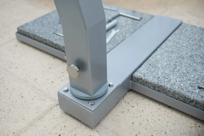 Close-up of steel framed cantilever umbrella base with grey granite pavers