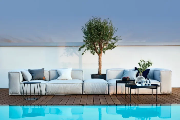 Plush minimalist outdoor sectional sofa with light grey upholstery poolside