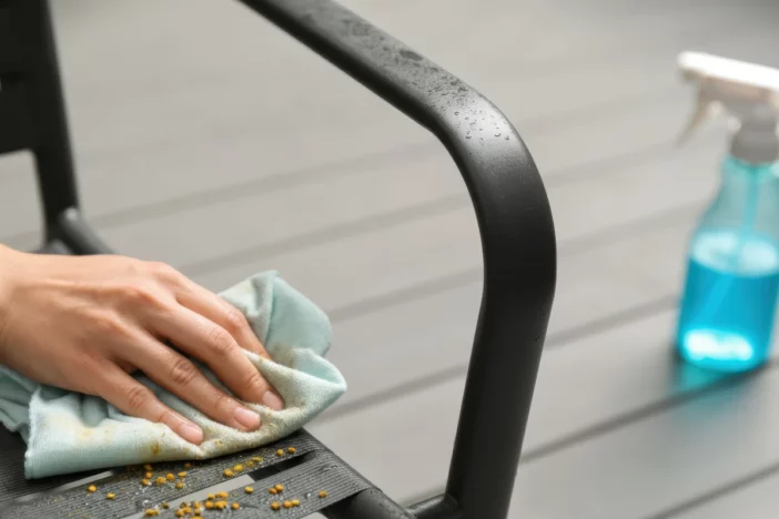 Close-up of hand with rag wiping debris from a black powder-coated aluminum chair